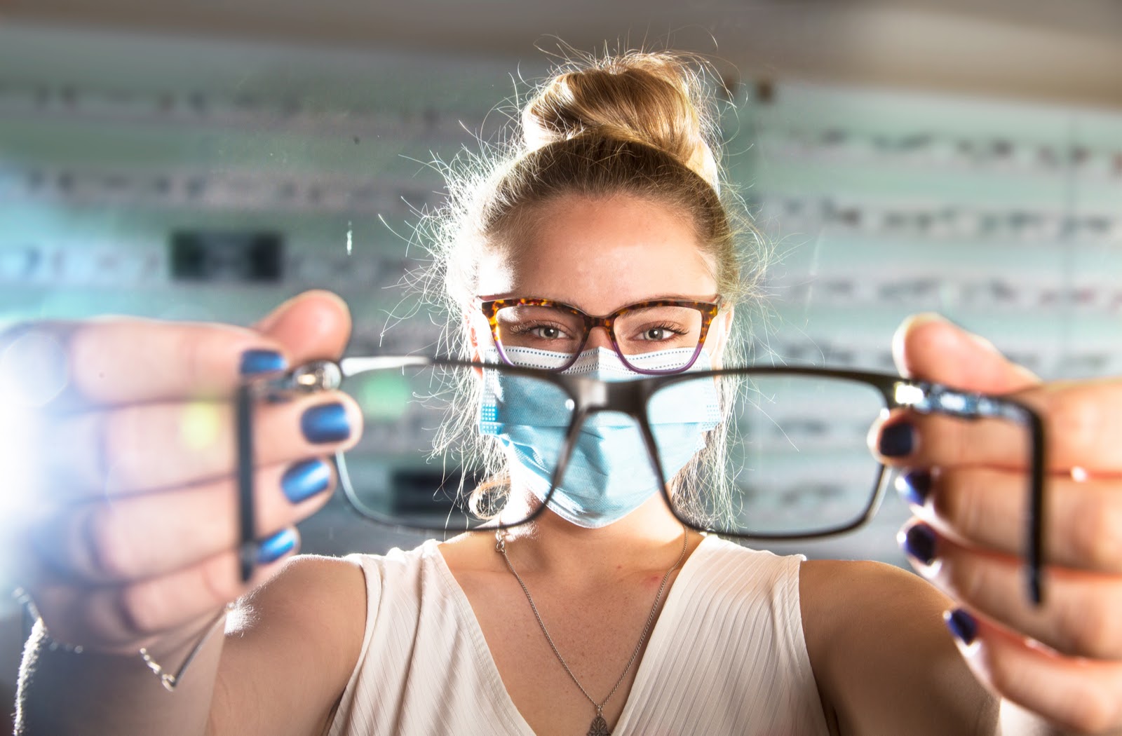 Optical Assistant wearing a face mask showing a pair of glasses