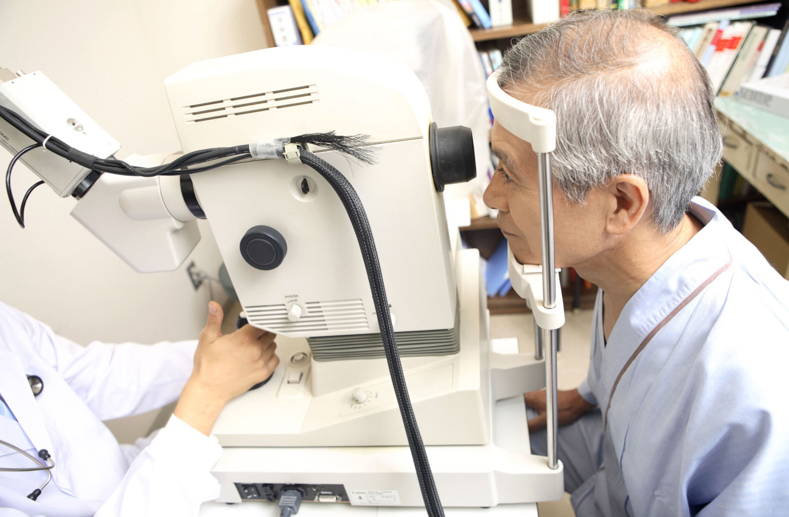 A senior man looking through a piece of medical equipment used for eye examinations.