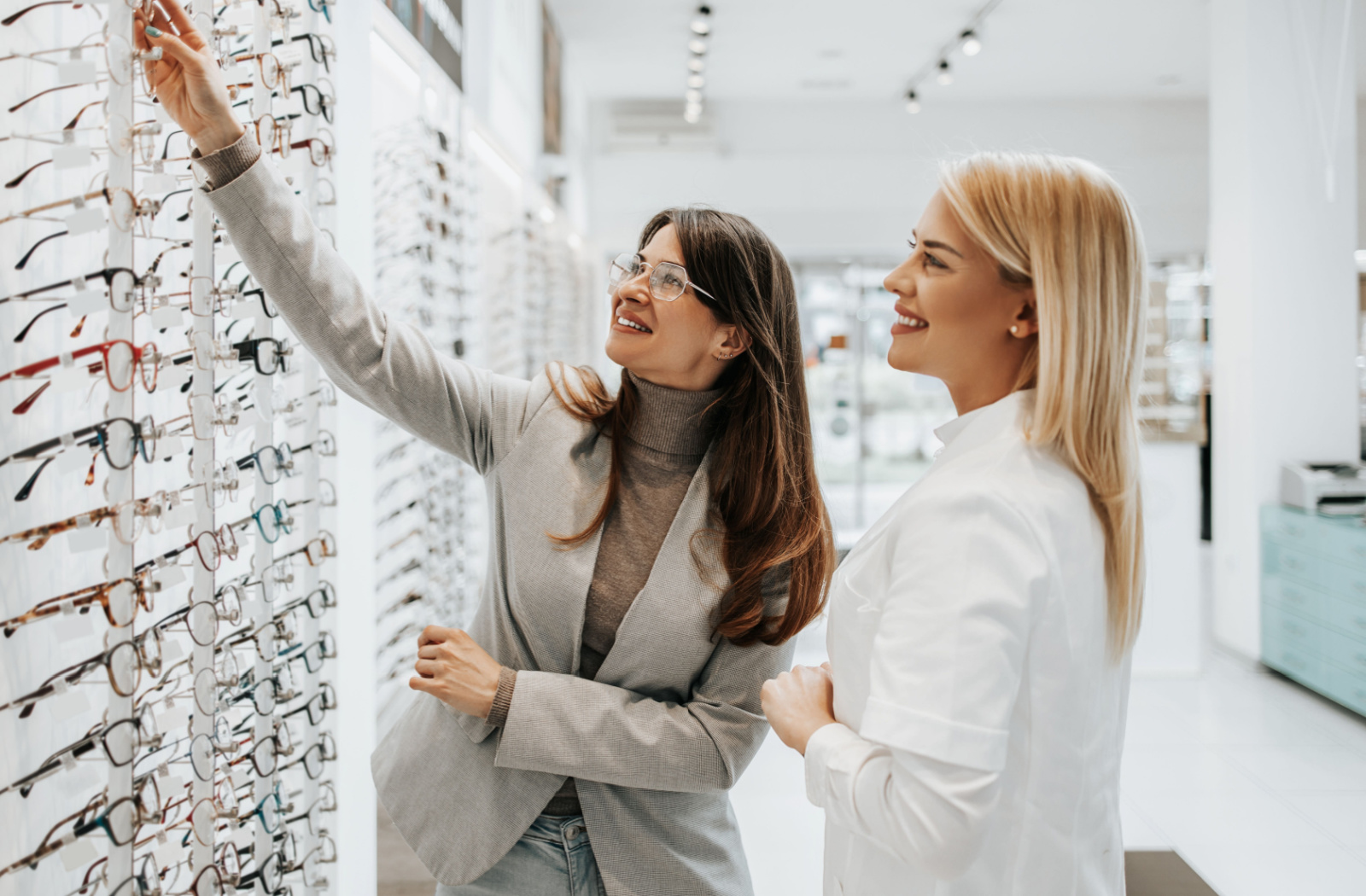 A patient and optician picking out a pair of frames from a wall of eyeglasses after a comprehensive eye exam with an optometrist.