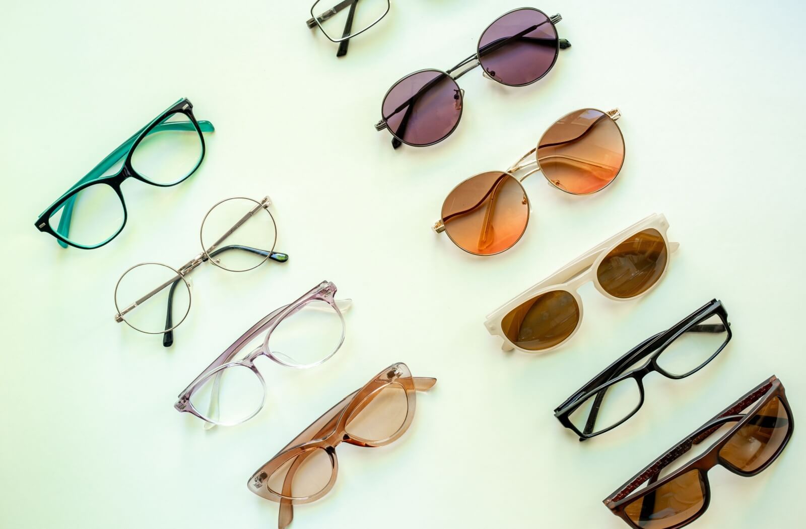 Several pairs of eyeglass frames are set out on a green table for a client to try on during an eyewear styling appointment.